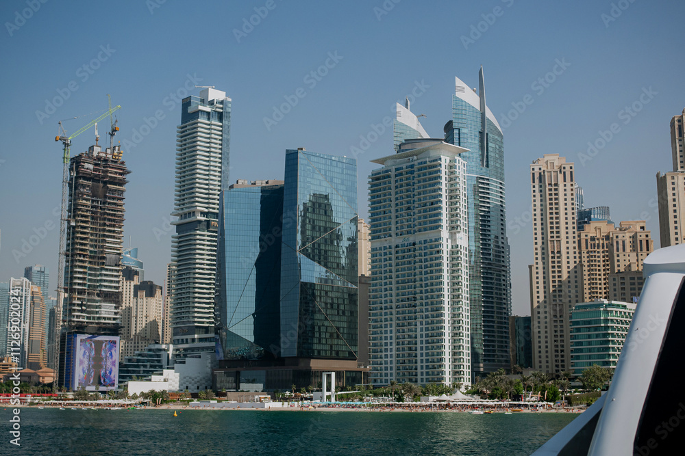 Fototapeta premium View from the yacht to High-rise buildings with glass facade against blue sky. Business center. Beach view. View from below