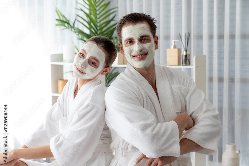 Obraz premium Blissful couple in bathrobe with facial cream mask enjoying serene ambiance of spa salon resort or hotel during holiday. Pampering face spa and skincare treatment with essence relaxation. Quiescent