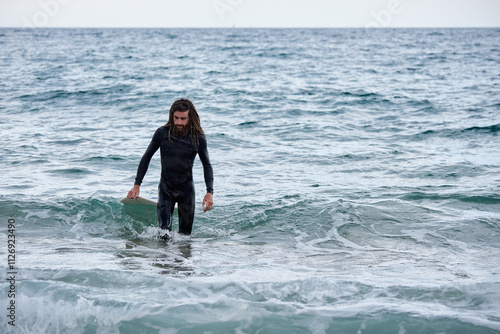 Surfer walking in water with board