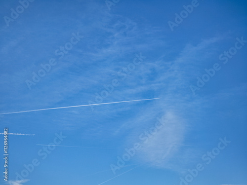 Airplane flying leaving white contrails in the blue sky over chamonix, france