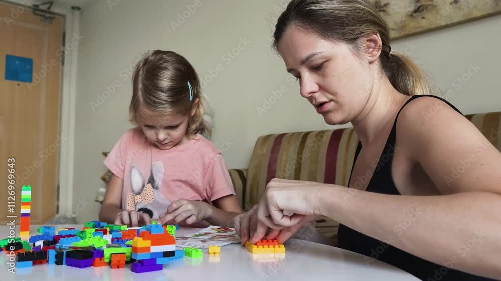 A mother and daughter engage in imaginative play with building blocks A mother and daughter engage in imaginative play with building blocks