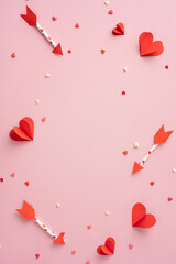 A vertical pink background adorned with red paper hearts and arrows symbolizes love and romance. Ideal for Valentine's Day celebrations and romantic themes