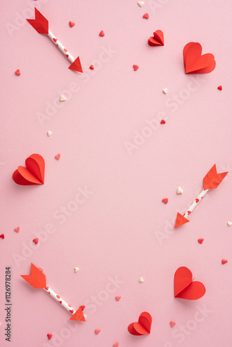 A vertical pink background adorned with red paper hearts and arrows symbolizes love and romance. Ideal for Valentine's Day celebrations and romantic themes photo