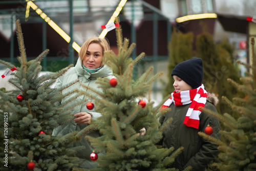 Happy mom and son buying Christmas tree on market for winter holidays. photo