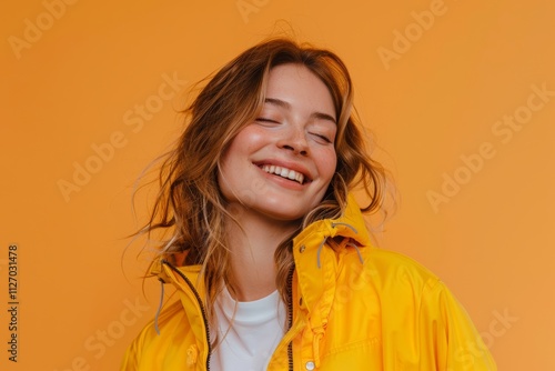 Portrait of a happy caucasian woman in her 30s wearing a lightweight packable anorak in front of pastel orange background photo