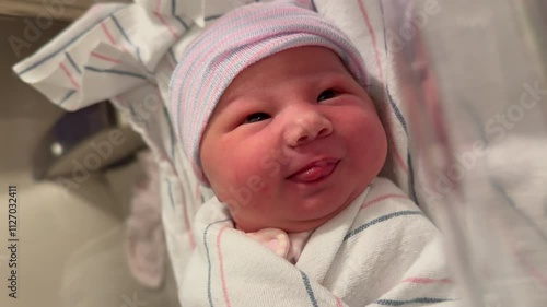 Vertical video of a newborn baby girl in a hospital. Baby just born in a hospital outfit. Newborn baby face expressions. Pediatrics concept