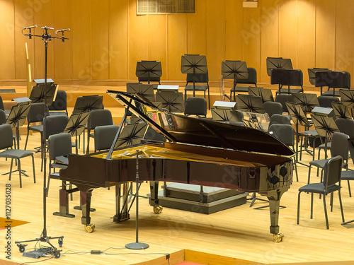 Grand piano in front of a raised podium for the director on a stage ready for a contemporary performance of a piano concerto composed by Johannes Brahms (1833-1897) in a modern church photo