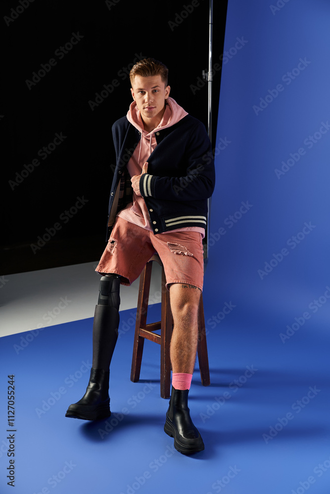 Young man on a stool shows off his prosthetic leg in stylish casual wear. Young man on a stool shows off his prosthetic leg in stylish casual wear.