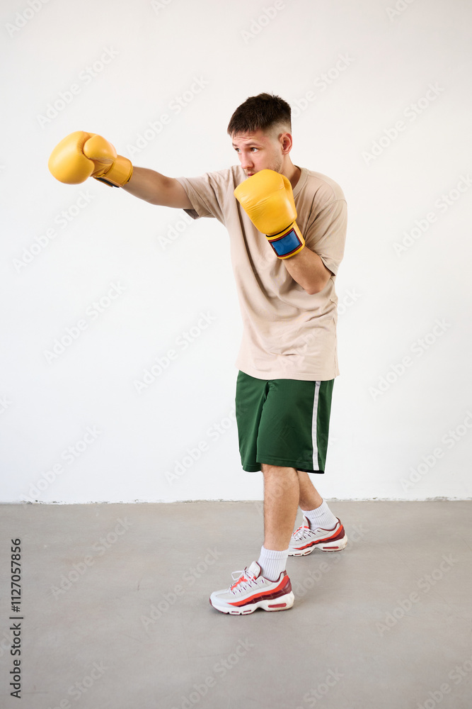 Handsome young guy shows a punch for protection in boxing with gloves Handsome young guy shows a punch for protection in boxing with gloves