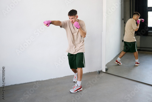 Young man with pink boxing bows shows punch