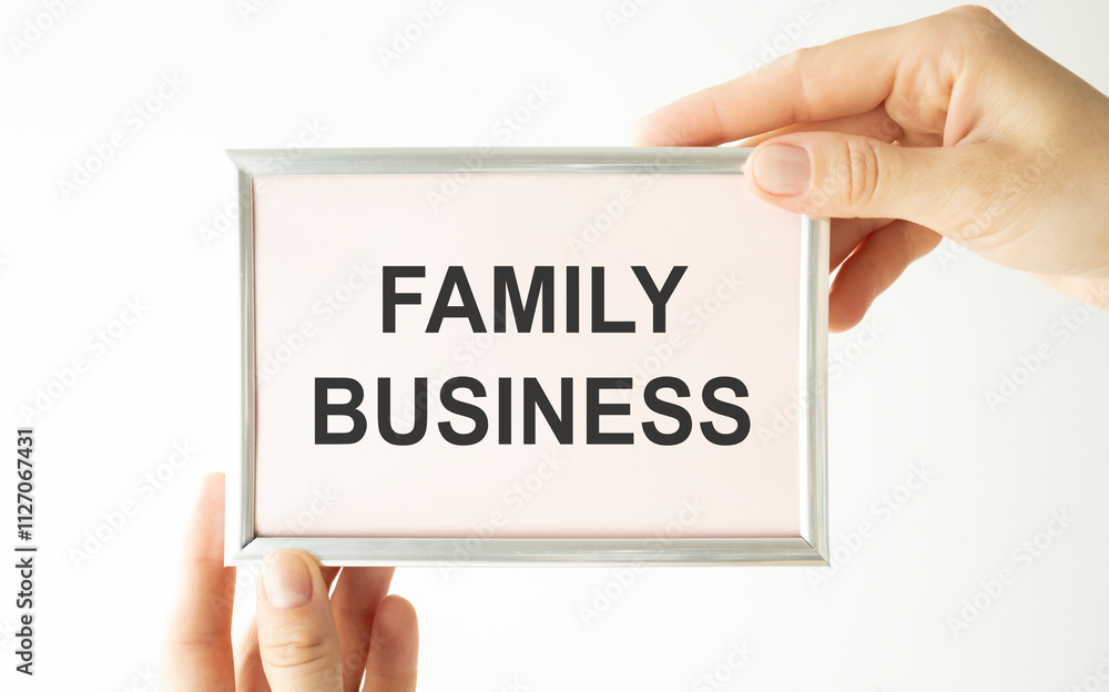 Closeup on businessman holding a card with text FAMILY BUSINESS, business concept image with soft focus background Closeup on businessman holding a card with text FAMILY BUSINESS, business concept image with soft focus background