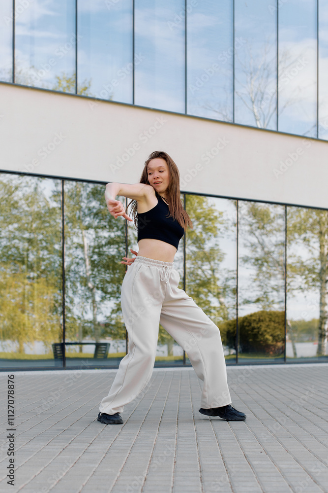A dancer performs a contemporary routine outdoors near a modern building with large glass windows in the afternoon light A dancer performs a contemporary routine outdoors near a modern building with large glass windows in the afternoon light
