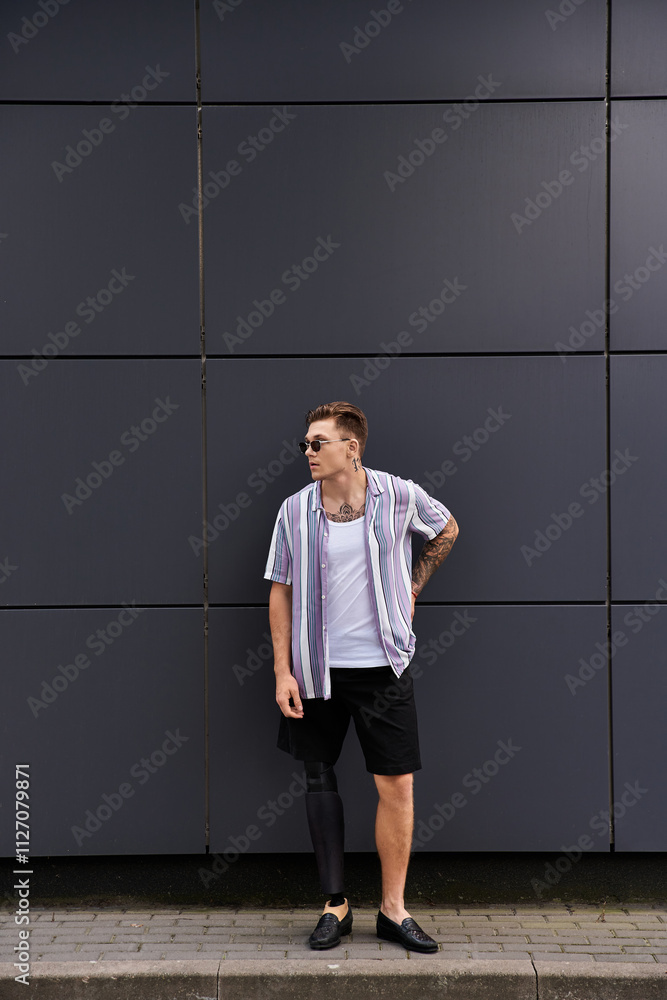 Stylish young man with a prosthetic leg poses confidently against a sleek wall. Stylish young man with a prosthetic leg poses confidently against a sleek wall.