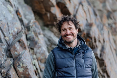 Portrait of a happy man in his 30s dressed in a breathable mesh vest on rocky cliff background photo