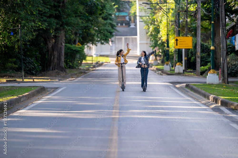 Two women riding scooters down a street Two women riding scooters down a street