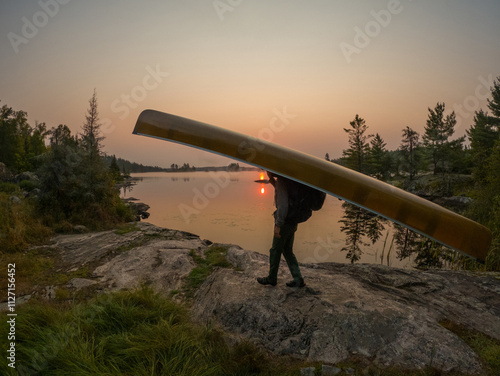 Portaging canoe near lake shore. Canoe portage at sunrise
