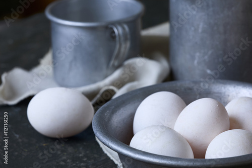 Still life with fresh eggs and aluminum dishes.