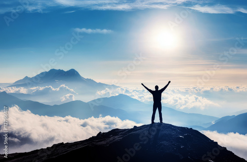 Silhouette of a man standing on top of a mountain with arms raised in victory, 