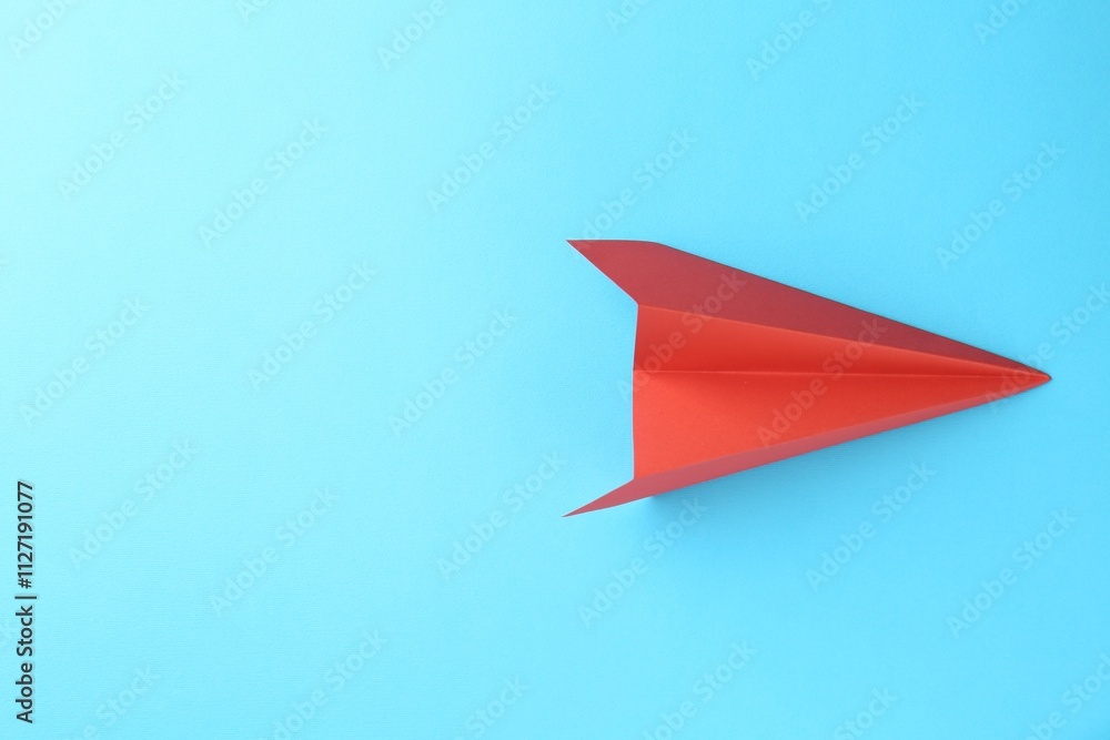 One handmade coral paper plane on light blue background, top view. Space for text One handmade coral paper plane on light blue background, top view. Space for text