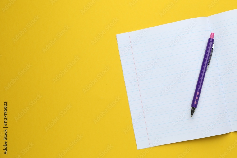 Open copybook and pen on yellow background, top view. Space for text Open copybook and pen on yellow background, top view. Space for text