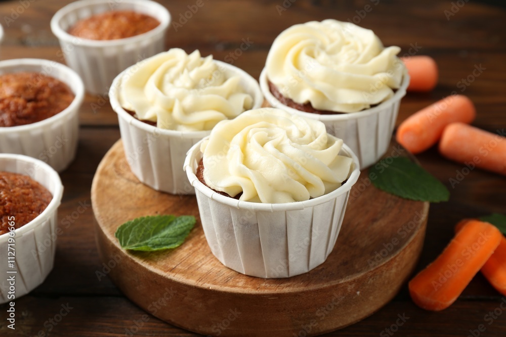Tasty carrot muffins and fresh vegetables on wooden table, closeup Tasty carrot muffins and fresh vegetables on wooden table, closeup