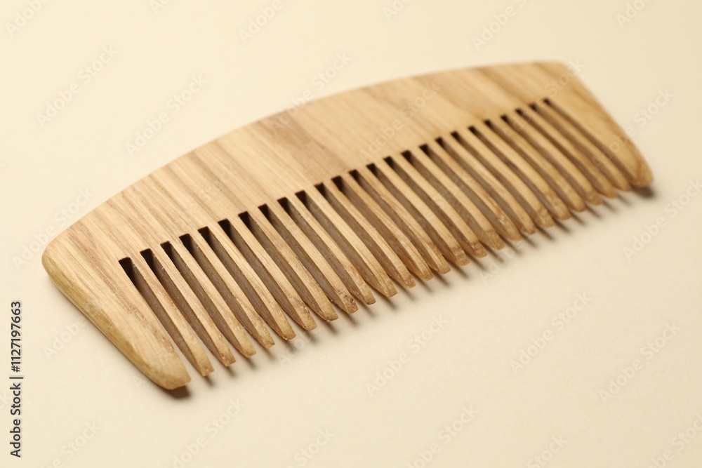 One wooden hair comb on beige background, closeup One wooden hair comb on beige background, closeup