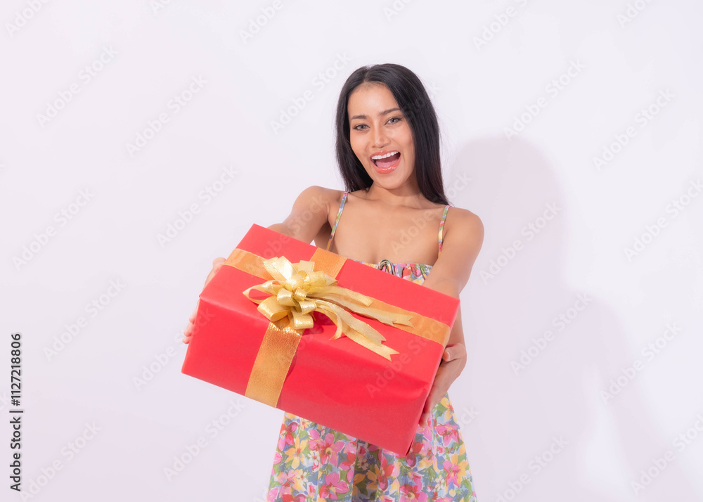Excited woman in a floral dress holding a large red gift box with a golden ribbon, celebrating a festive occasion, holiday, or special event with joy and happiness Excited woman in a floral dress holding a large red gift box with a golden ribbon, celebrating a festive occasion, holiday, or special event with joy and happiness