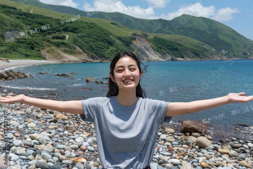 Woman joyfully embracing the fresh ocean breeze with arms outstretched on a beautiful rocky beach