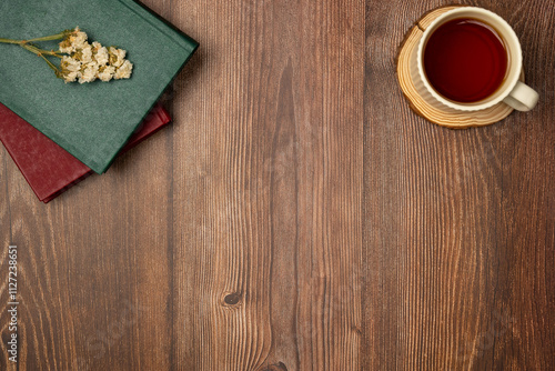 Books with cup of tea on wooden background from above. Flat lay, top view. Copy space