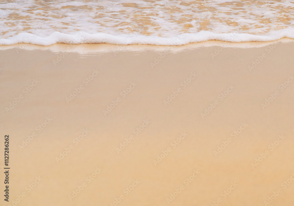 Clean sandy beach by the ocean, small waves with foam washing the shore, close-up view of golden yellow sand from copy space. Clean sandy beach by the ocean, small waves with foam washing the shore, close-up view of golden yellow sand from copy space.