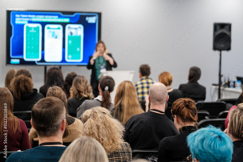 Obraz premium Diverse group of individuals attending a presentation about innovative technology solutions, engaging with speaker and digital display. Setting represents modern education and professional growth.
