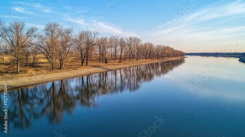 Aerial view of tranquil river reflecting trees along a serene shore under a clear blue sky