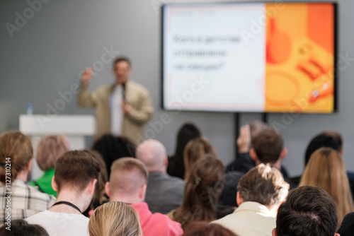 Professional speaking at conference room engaging audience with presentation. Focus on screen and speaker.