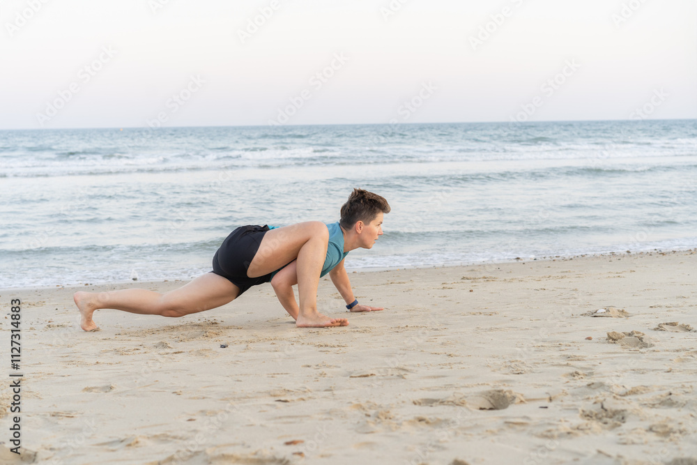 Sporty woman is engaged in animal flow gymnastics outdoors on sea beach. Female trains with Animal Flow workout to elevate her body weight workout. Innovative animal instinct fitness sport movement. Sporty woman is engaged in animal flow gymnastics outdoors on sea beach. Female trains with Animal Flow workout to elevate her body weight workout. Innovative animal instinct fitness sport movement.