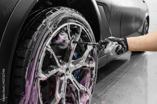 Professional car wash. Close up view of car wheel being washed with the brush and soap