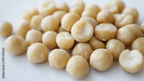 Macadamia nuts piled on a clean white surface showcasing their smooth texture and natural color ideal for culinary or health-related themes