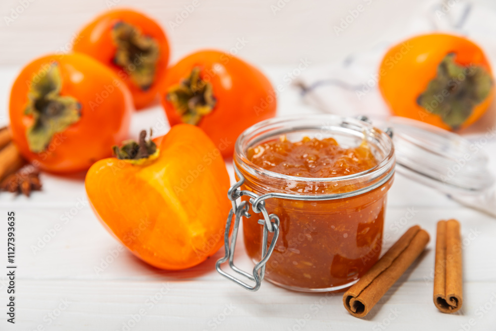 Persimmon jam with slices of ripe persimmon on wooden textured table. Delicious persimmon jam. Marmalade. Healthy sweets. Vegan. Close-up. Space for text. Copy space.