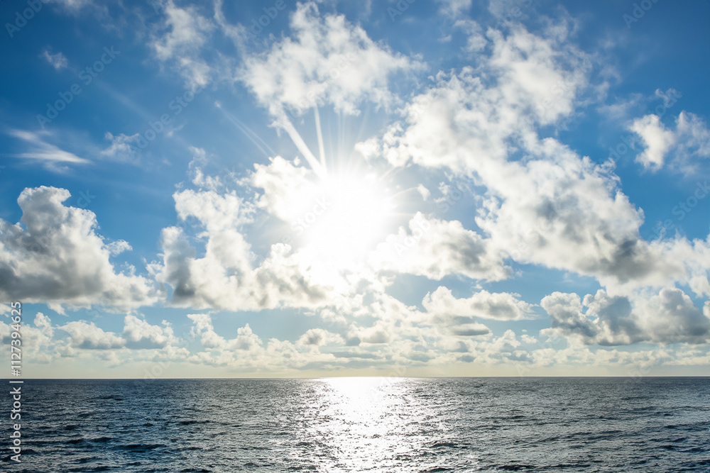 Obraz premium The sun shines brightly over the ocean in this photo. Clouds and sea in the sky. A sea blue sky with a sun glare. A blue sky with clouds and blue clouds glares at lifestyle the sea sun.