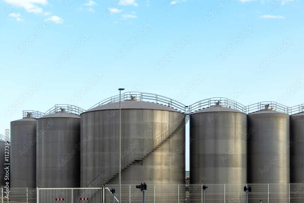 Row of Industrial Silos or Tanks Under a Clear Sky. Row of Industrial Silos or Tanks Under a Clear Sky.