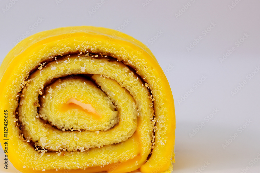 Fototapeta premium Yellow cake with swirl on top. Roll of yellow and gray on gray background. A roll of gray lies on a yellow background of jam sweetness. A roll of sweet jam lies on a gray lifestyle background.