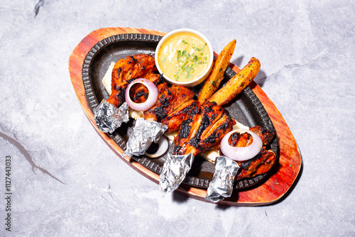 Chicken Tangdi kabab with naan bread, mayo dip, onion and fries served on a sizzling plate isolated on grey background side view of indian, bangladeshi and pakistani bbq food photo