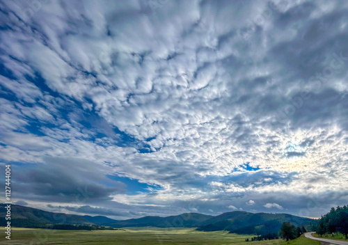 landscape with moving clouds over mountains and field
