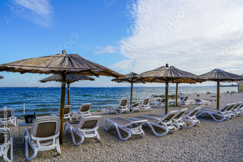 Fototapeta Naklejka Na Ścianę i Meble -  Empty beach cafe without visitors after the end of the season, reed sunshades, empty sunbeds