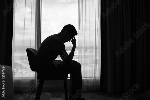 Sad man in a dark room full of desperation thoughts. Portrait of thoughtful sad man alone. Fear, sadness, abuse, depression, addiction.	