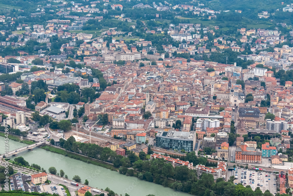 Fototapeta premium Breathtaking aerial view of city of Trento nestled amidst cloud covered mountainous landscape in Trentino Alto Adige, Italy. Vantage point from Terrazza Panoramica Busa Degli Orsi. Tourist destination