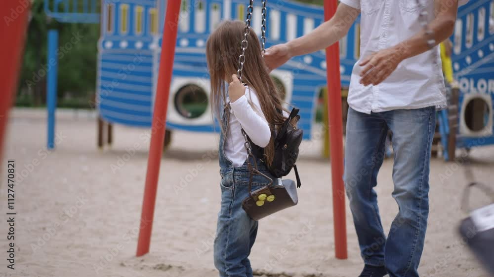 On a sunny day, a young girl joyfully explores a swing at a playground, highlighting delightful moments of childhood On a sunny day, a young girl joyfully explores a swing at a playground, highlighting delightful moments of childhood