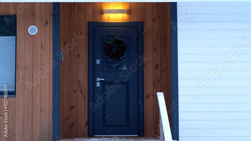 entrance to a country house with a wreath on the door in winter, the light on the porch comes on