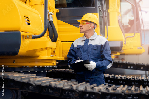 Foto Worker with tablet inspects bulldozer at coal and sand quarry, concept industry
