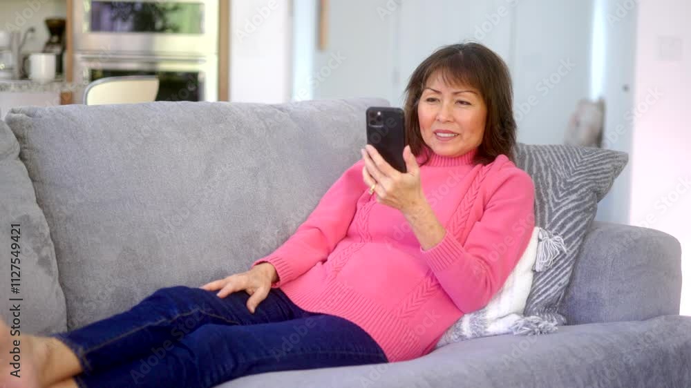 Cheerful woman smiling laughing enjoying talking using tablet video chat relaxing sitting on home sofa. Cheerful woman smiling laughing enjoying talking using tablet video chat relaxing sitting on home sofa.