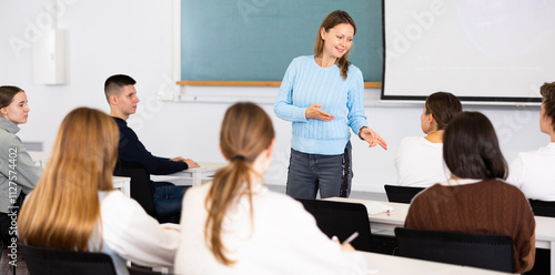 Confident young female professor talks to students in classroom